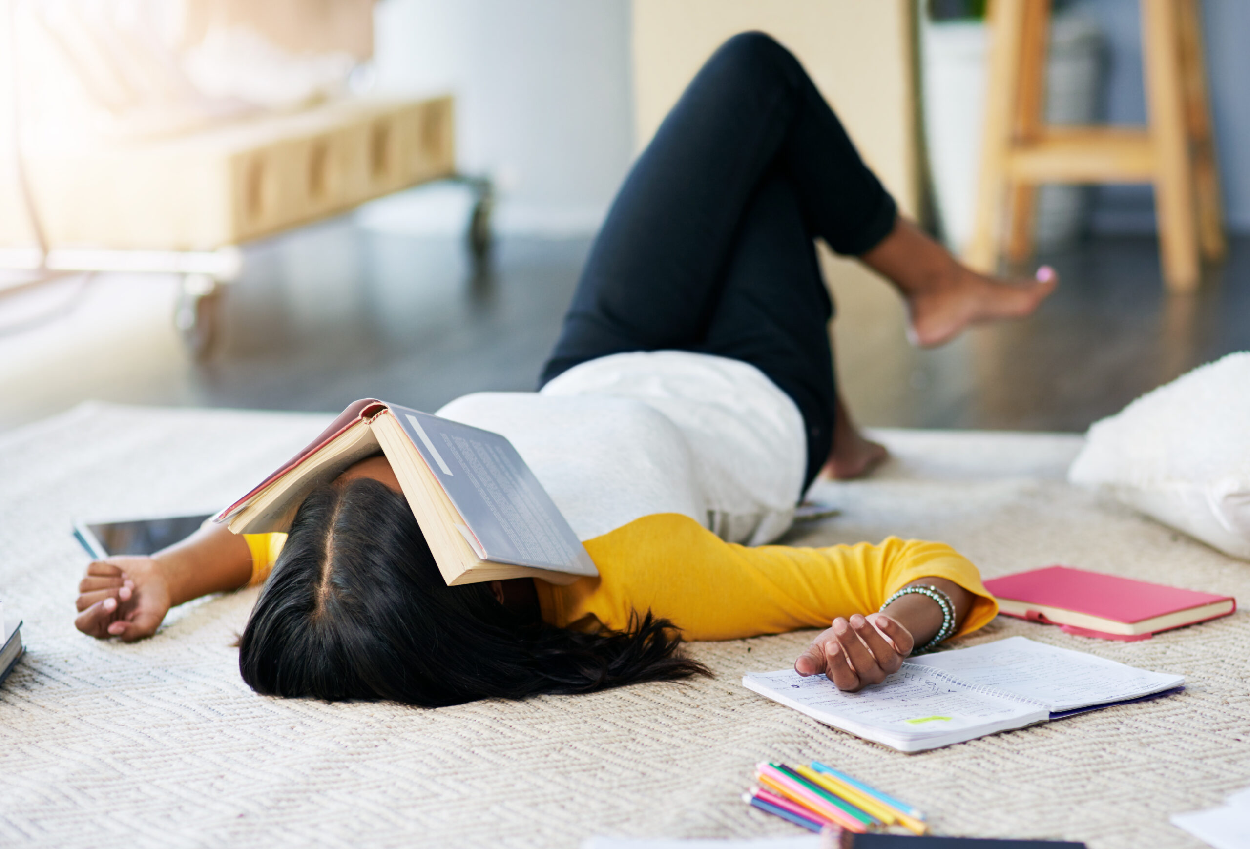 Student with their head in a textbook, overwhelmed by how much there is to get through